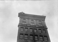 J. Reynolds, Performing Acrobatic And Balancing Acts On High Cornice Above 9th Street, N.W., 1917. Creator: Harris & Ewing