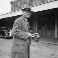 John Laing holding a Rolleiflex camera outside Bournemouth train station, 30/05/1953. Creator: John Laing plc