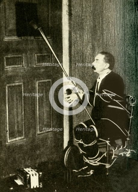 John Nevil Maskelyne performs a 'spirit cabinet illusion', c1910. Creator: Unknown.