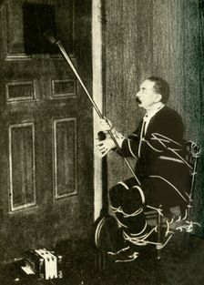 John Nevil Maskelyne performs a spirit cabinet illusion c1910. Creator: Unknown