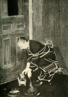 John Nevil Maskelyne performs a spirit cabinet illusion c1910. Creator: Unknown