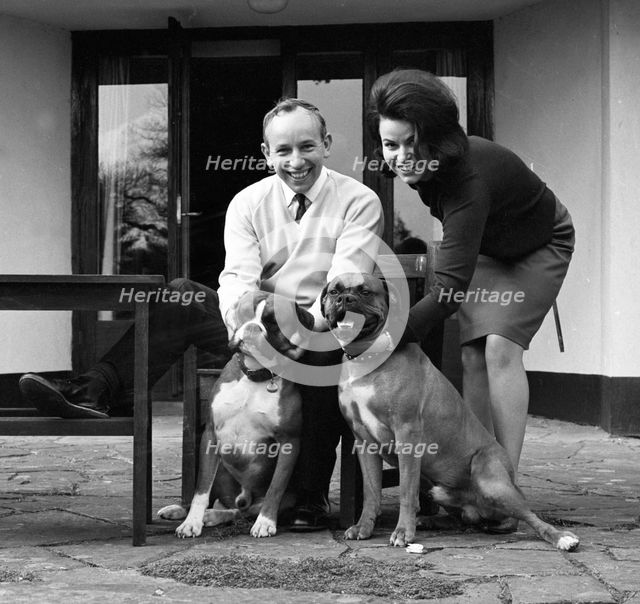 John Surtees relaxes at home with his wife and pet dogs in 1966. Creator: Unknown.