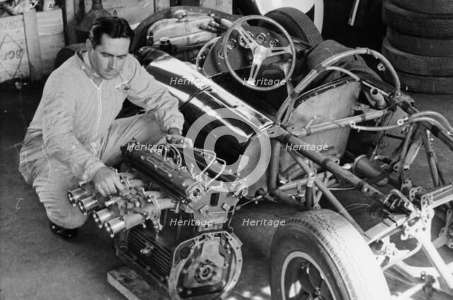 Jack Brabham inspecting the engine of a car. Artist: Unknown