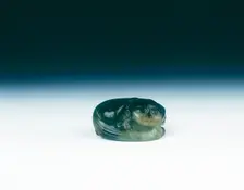 Jade cat sitting curled up scratching its ear with one eye closed, Yuan dynasty, China, 1279-1368. Creator: Unknown