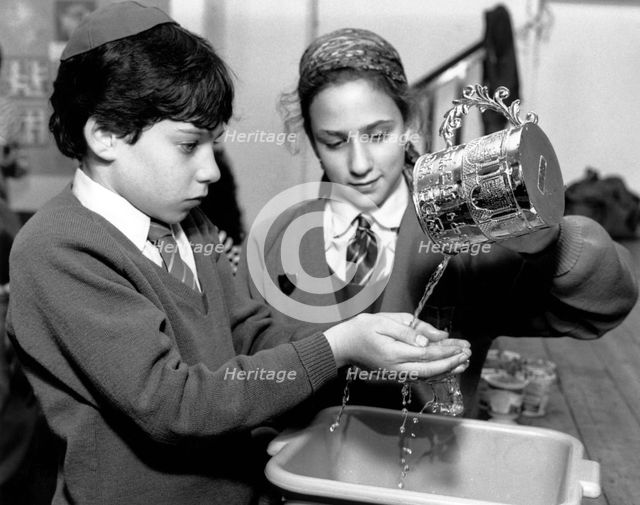 Jewish children performing ritual hand-washing, April 1991. Creator: Sidney Harris.