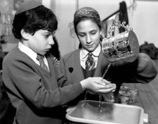 Jewish children performing ritual hand-washing, April 1991. Creator: Sidney Harris