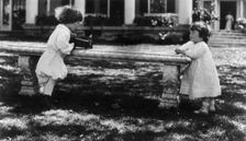 One child aiming camera, on bench, at another child, Washington, D.C., between c1890 and c1910. Creator: Frances Benjamin Johnston