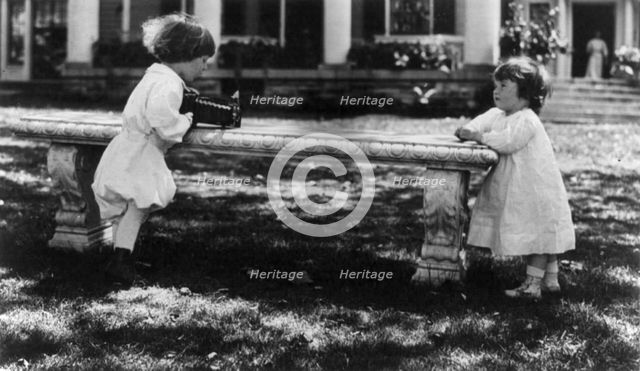 One child aiming camera, on bench, at another child, Washington, D.C., between c1890 and c1910. Creator: Frances Benjamin Johnston.