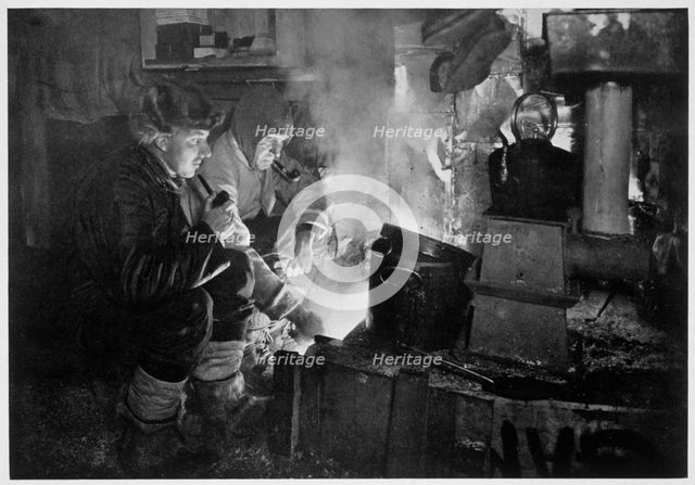 'Oates and Meares at the Blubber Stove in the Stables', Antarctica, 1911. Creator: Herbert Ponting.