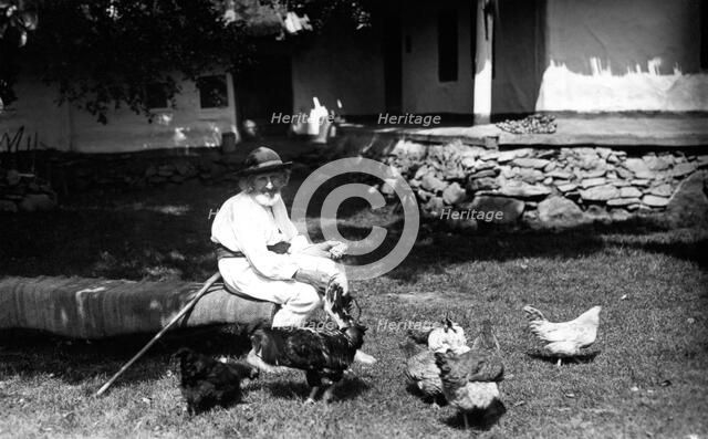 Old man feeding chickens, Bistrita Valley, Moldavia, north-east Romania, c1920-c1945. Artist: Adolph Chevalier