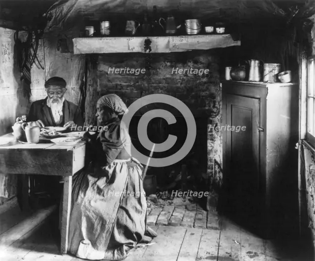 Old African American couple eating at the table by fireplace, rural Virginia, 1899 or 1900. Creator: Frances Benjamin Johnston.