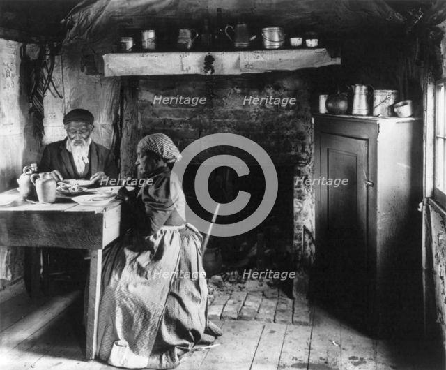 Old African American couple eating at the table by fireplace, rural Virginia, 1899 or 1900. Creator: Frances Benjamin Johnston.