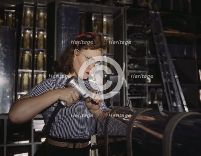 Operating a hand drill at the North American Aviation, Inc., a woman is in the control..., 1942. Creator: Alfred T Palmer.