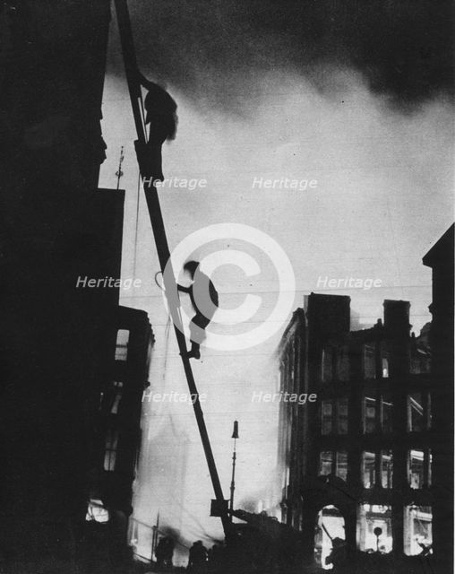 'Out in the Blitz, silhouetted aganinst the light of fires, rescue men climb into a building in St.  Artist: Unknown.