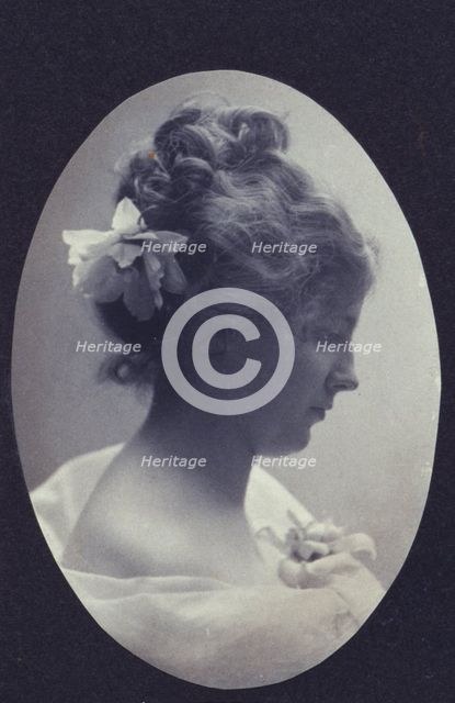 Oval portrait of woman with a flower in her hair and a corsage on her dress, c1900. Creator: Fannie L. Elton.