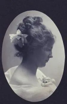 Oval portrait of woman with a flower in her hair and a corsage on her dress, c1900. Creator: Fannie L. Elton