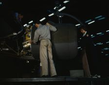 Lowering an engine in place in assembling a C-87...Consolidated Aircraft..., Fort Worth, Texas, 1942 Creator: Howard Hollem