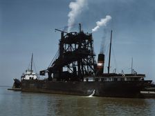 Loading coal into a freighter at one of the Pennsylvania Railroad docks, Sandusky, Ohio, 1943. Creator: Jack Delano