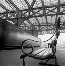 Looking along a bench with curved wrought iron arms on a platform at Waterloo Station, 1960-1972. Creator: John Gay