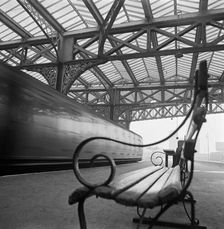 Looking along a bench with curved wrought iron arms on a platform at Waterloo Station, 1960-1972. Creator: John Gay