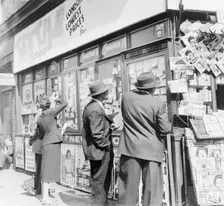 Looking at accomodation notices and job vacancy advertisements in a newsagents window, c1955. Creator: Henry Grant