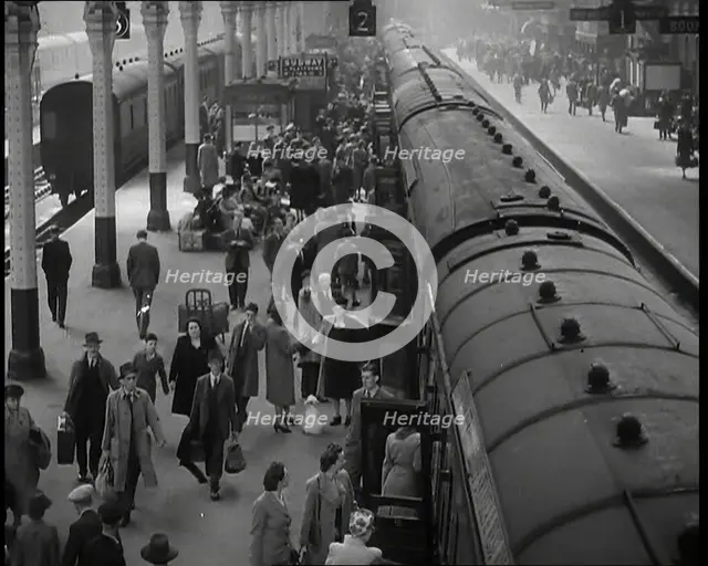 Looking Down Along a Train Platform With Passengers Walking Along, Embarking and Disembark..., 1938. Creator: British Pathe Ltd.