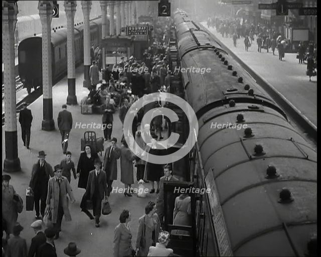 Looking Down Along a Train Platform With Passengers Walking Along, Embarking and Disembark..., 1938. Creator: British Pathe Ltd.