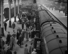 Looking Down Along a Train Platform With Passengers Walking Along, Embarking and Disembark..., 1938. Creator: British Pathe Ltd