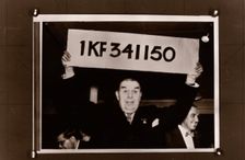 Lord Mackintosh holds up the first winning premium bond number, 1966