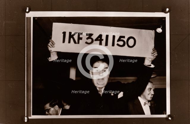 Lord Mackintosh holds up the first winning premium bond number, 1966. Artist: Unknown