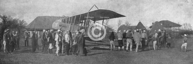 'La retraite de nos aviateurs par l'Albanie; Biplan entoure par la population masculine..., 1916. Creator: Unknown.