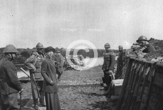'La Reine des Belges sur les lignes de L'Yser; Un soldat (a droite) joue un air de violon', 1916. Creator: Unknown.