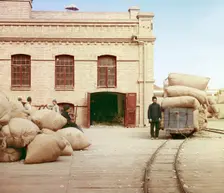 Labourers loading sacks onto railway at factory warehouse, between 1905 and 1915. Creator: Sergey Mikhaylovich Prokudin-Gorsky