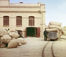 Labourers loading sacks onto railway at factory warehouse, between 1905 and 1915. Creator: Sergey Mikhaylovich Prokudin-Gorsky
