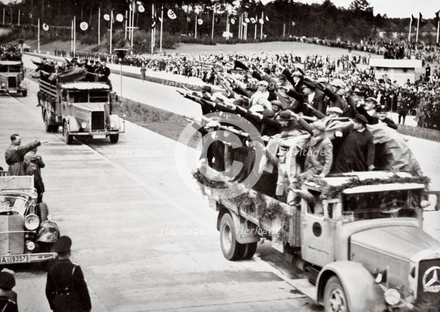 Labourers salute Hitler from packed trucks on a Nazi-built road, 1936.  Creator: Unknown.