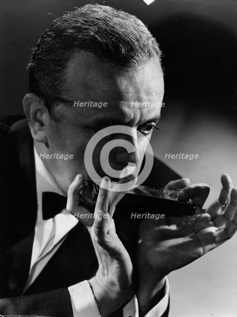 Larry Adler (1914-2001), Musician, playing his harmonica, c1940s. Creator: Unknown.