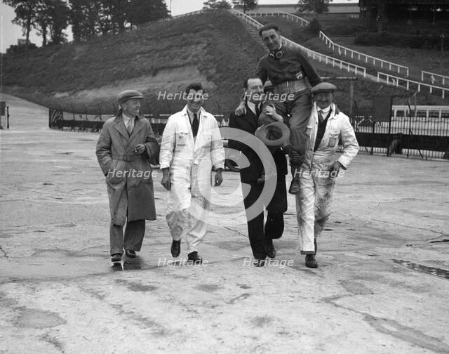 Leon Cushman being carried aloft after making a successful speed record attempt, Brooklands, 1931. Artist: Bill Brunell.