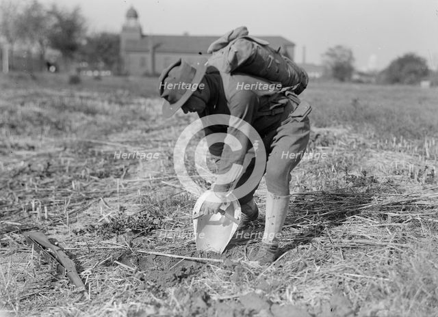 Leonard D. Mahon with steel helmet he invented that could be used as shovel, 1917. Creator: Harris & Ewing.