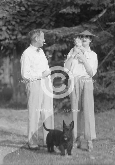 Leonard, Mr. and Mrs., with cat and dog, standing outdoors, between 1926 and 1938. Creator: Arnold Genthe.