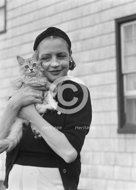 Leonard, Mrs., with cat, standing outdoors, between 1926 and 1938. Creator: Arnold Genthe.