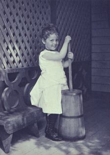Little girl wearing white chemise, beaded necklace, and high-button shoes on porch with..., c1900. Creator: Unknown