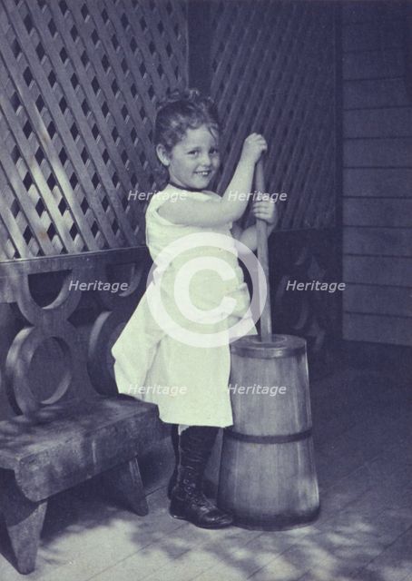 Little girl wearing white chemise, beaded necklace, and high-button shoes on porch with..., c1900. Creator: Unknown.