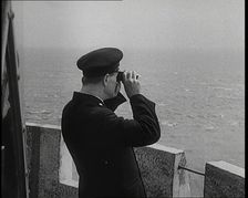 Lighthouse Keeper Looking Through Binoculars at the Turbulent Sea, 1920s. Creator: British Pathe Ltd