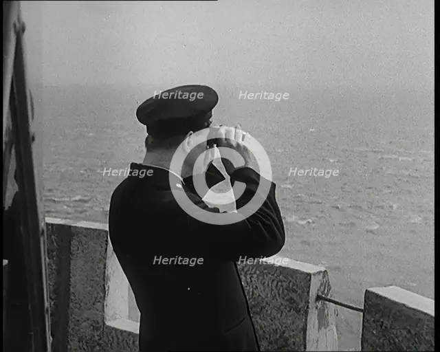 Lighthouse Keeper Looking Through Binoculars at the Turbulent Sea, 1920s. Creator: British Pathe Ltd.