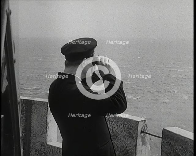 Lighthouse Keeper Looking Through Binoculars at the Turbulent Sea, 1920s. Creator: British Pathe Ltd.