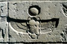 Limestone relief of a scarab beetle and vulture wings under a disk of the sun, Edfu, Egypt