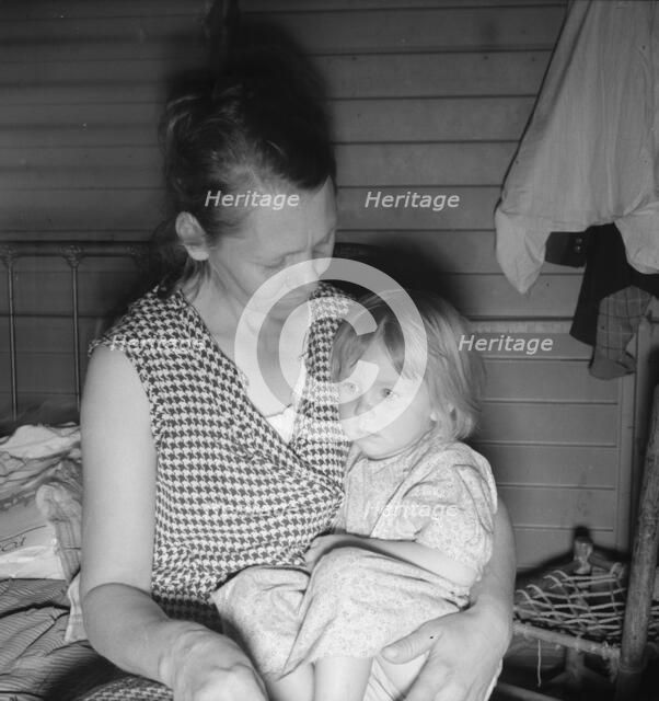 Mother from Oklahoma, awaits visit of resident nurse for sick baby, FSA camp, Farmersville, CA, 1939 Creator: Dorothea Lange.