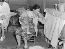Mother from Oklahoma tends baby with dysentery, FSA camp, Tulare County, California, 1939. Creator: Dorothea Lange