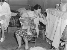 Mother from Oklahoma tends baby with dysentery, FSA camp, Tulare County, California, 1939. Creator: Dorothea Lange