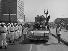 Models and a Cadillac on a parade, USA, (c1959?)